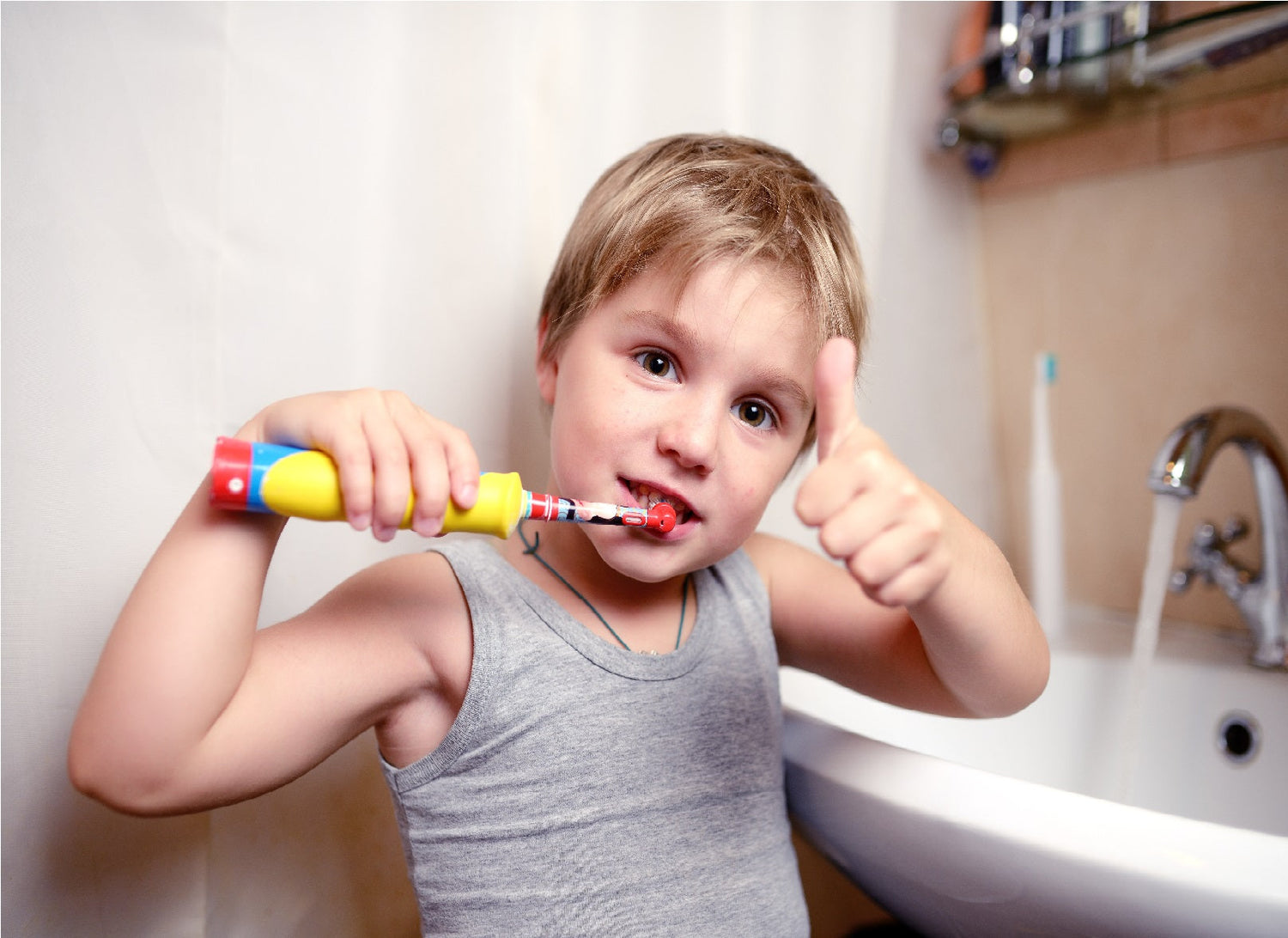 kind met een elektrische tandenborstel duimpje omhoog